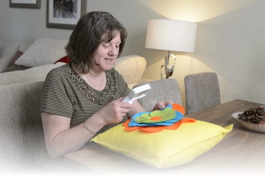 a lady sat down reading something through a handheld magnifier