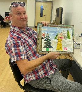 a man proudly showing a painting to the camera
